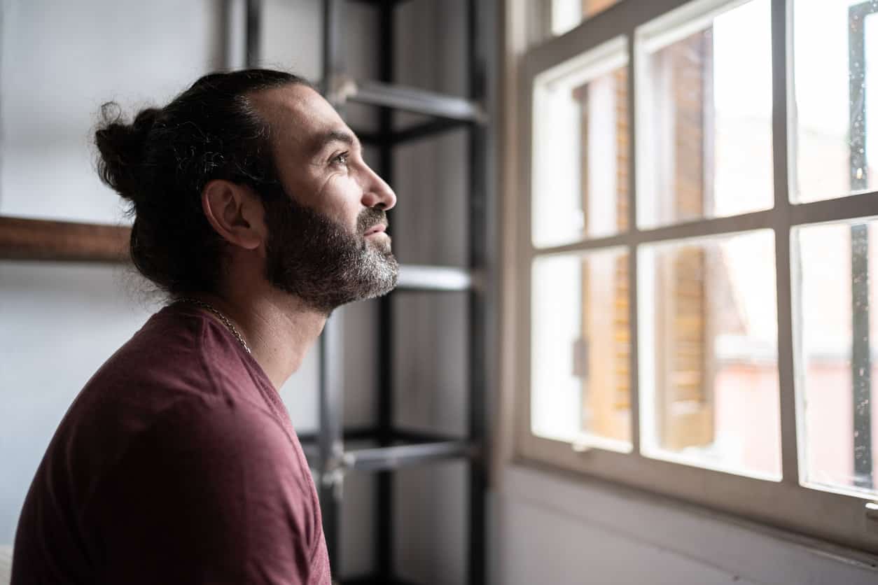 Man looking through the window at home