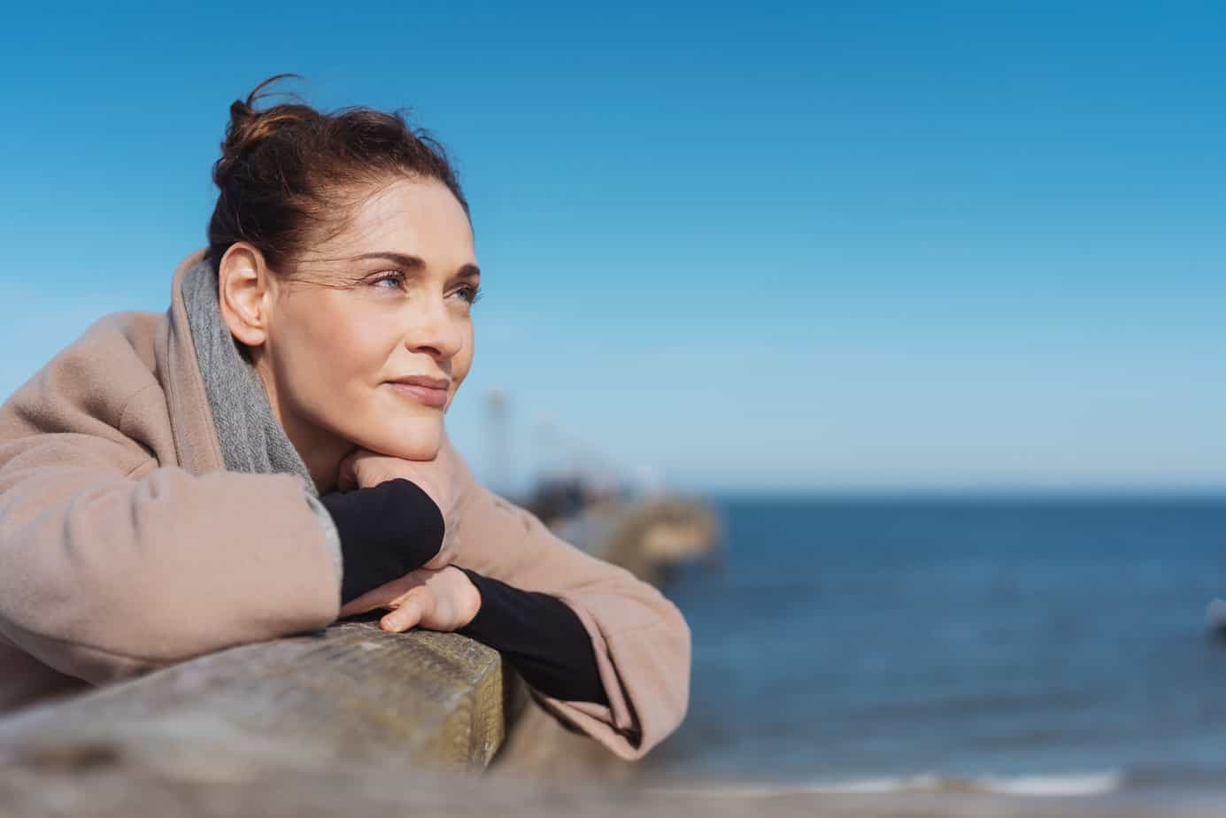 woman staring off into the ocean moving on from regret and looking hopeful