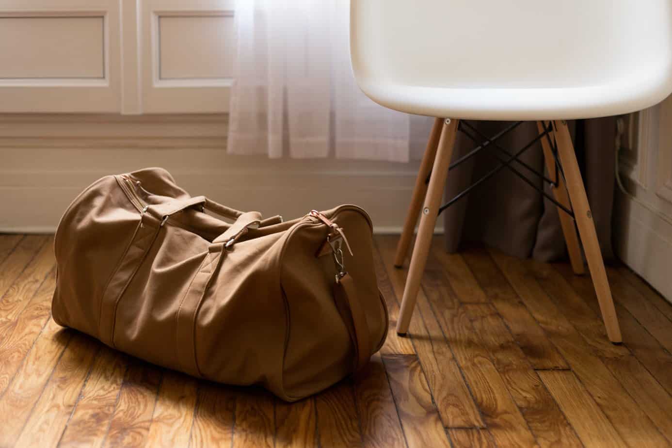 A packed duffle bag on a wooden floor.