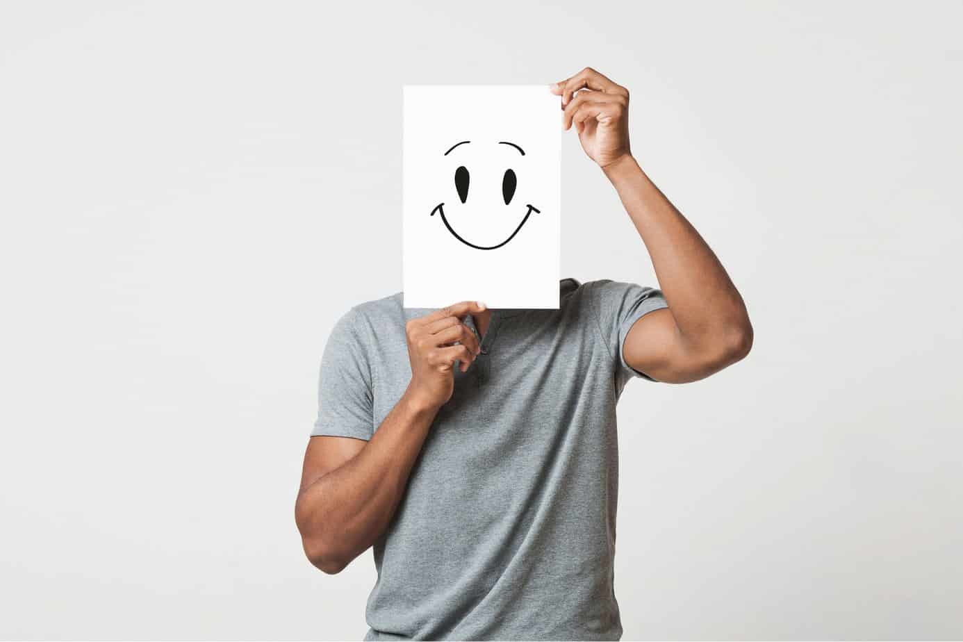 Putting smiling face on. Black man holding paper with smiley face printed on, happiness and joy concept