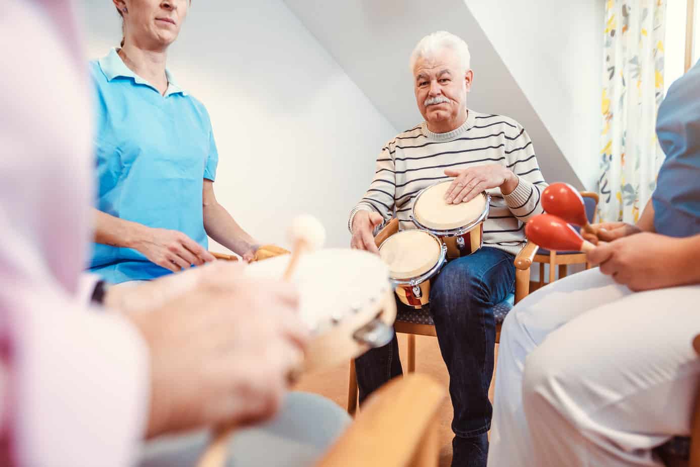 Seniors in nursing home making music with rhythm instruments as musical therapy