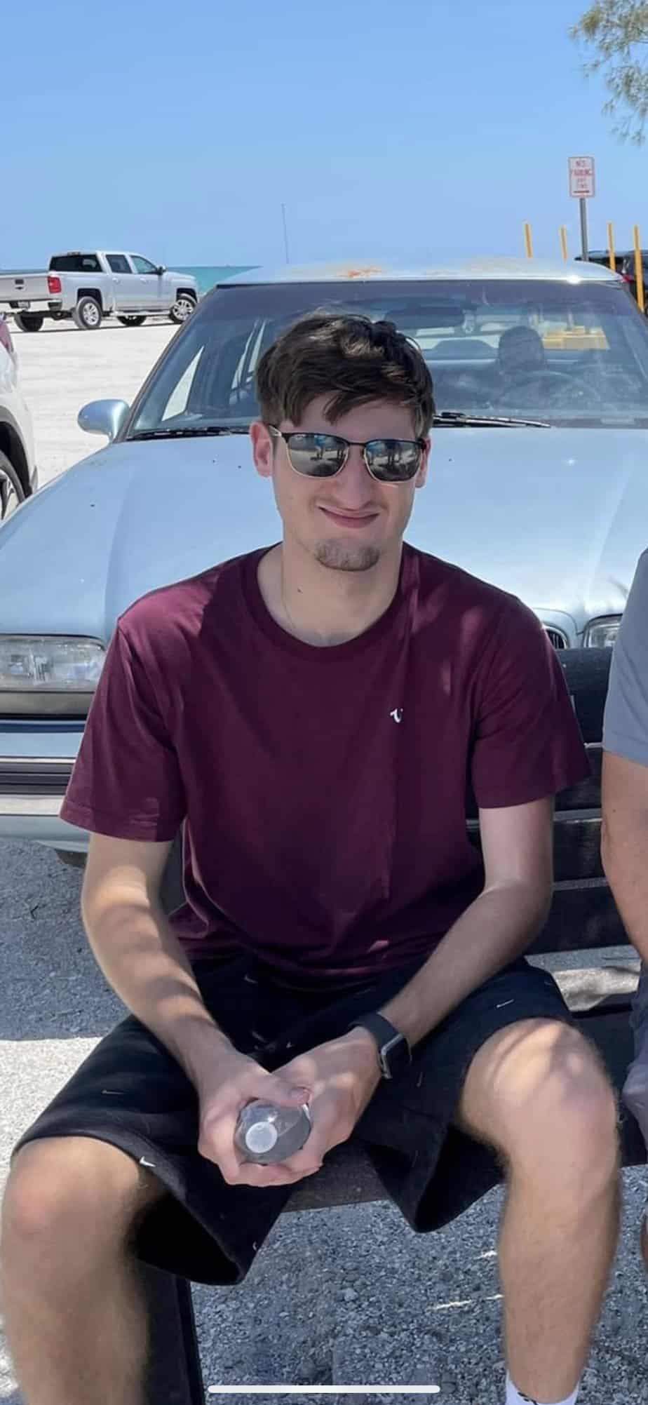 young male sitting on car with sunglasses
