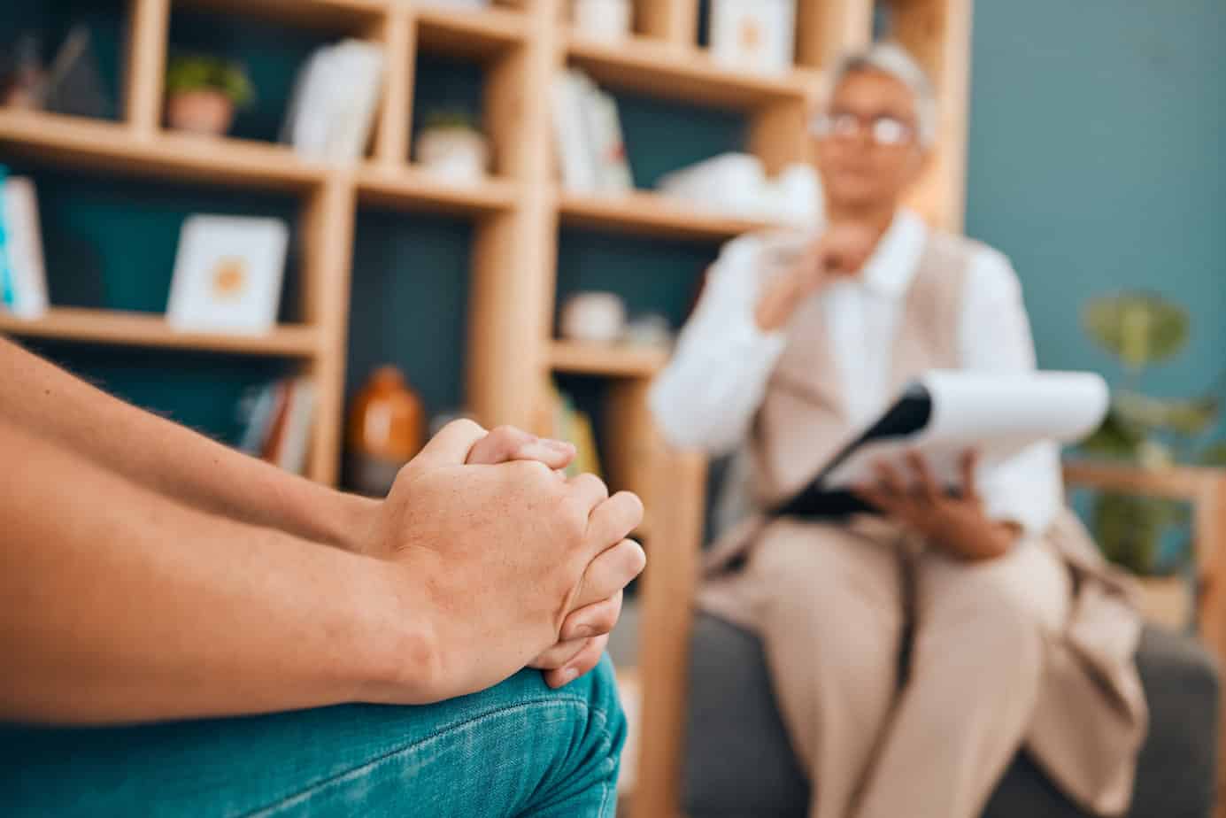 close up of person's hands in therapy room sitting across from therapist