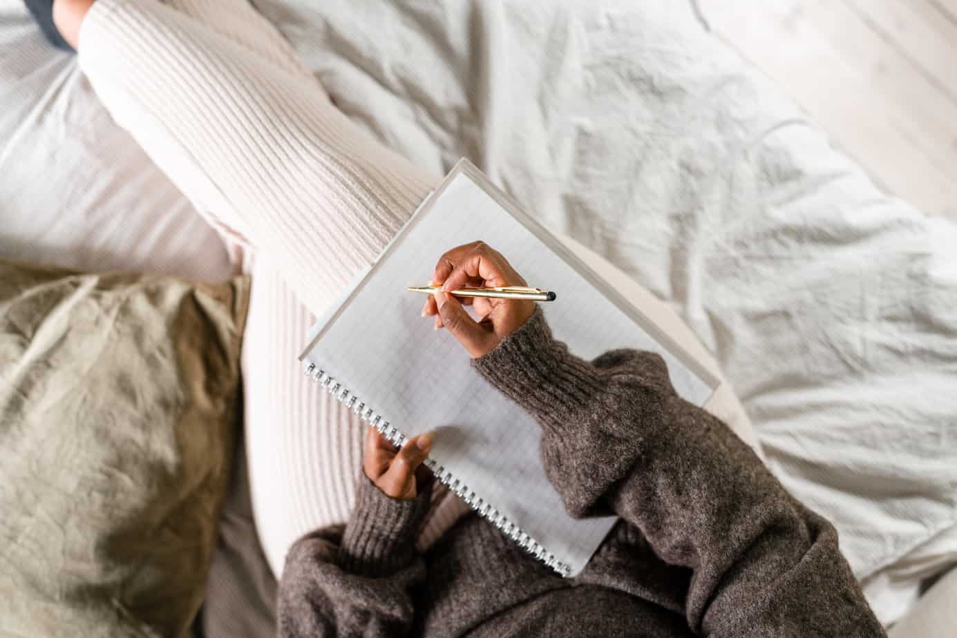 aerial view of woman practicing somatic writing in bed